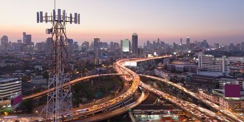 Telecommunication tower with 5G cellular network antenna on city background