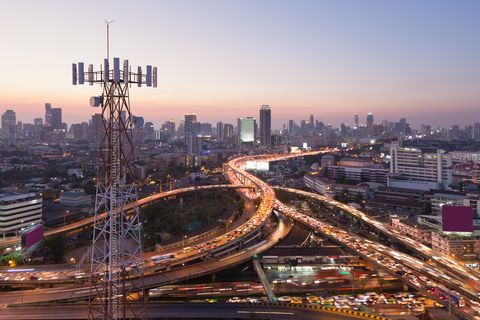 Telecommunication tower with 5G cellular network antenna on city background